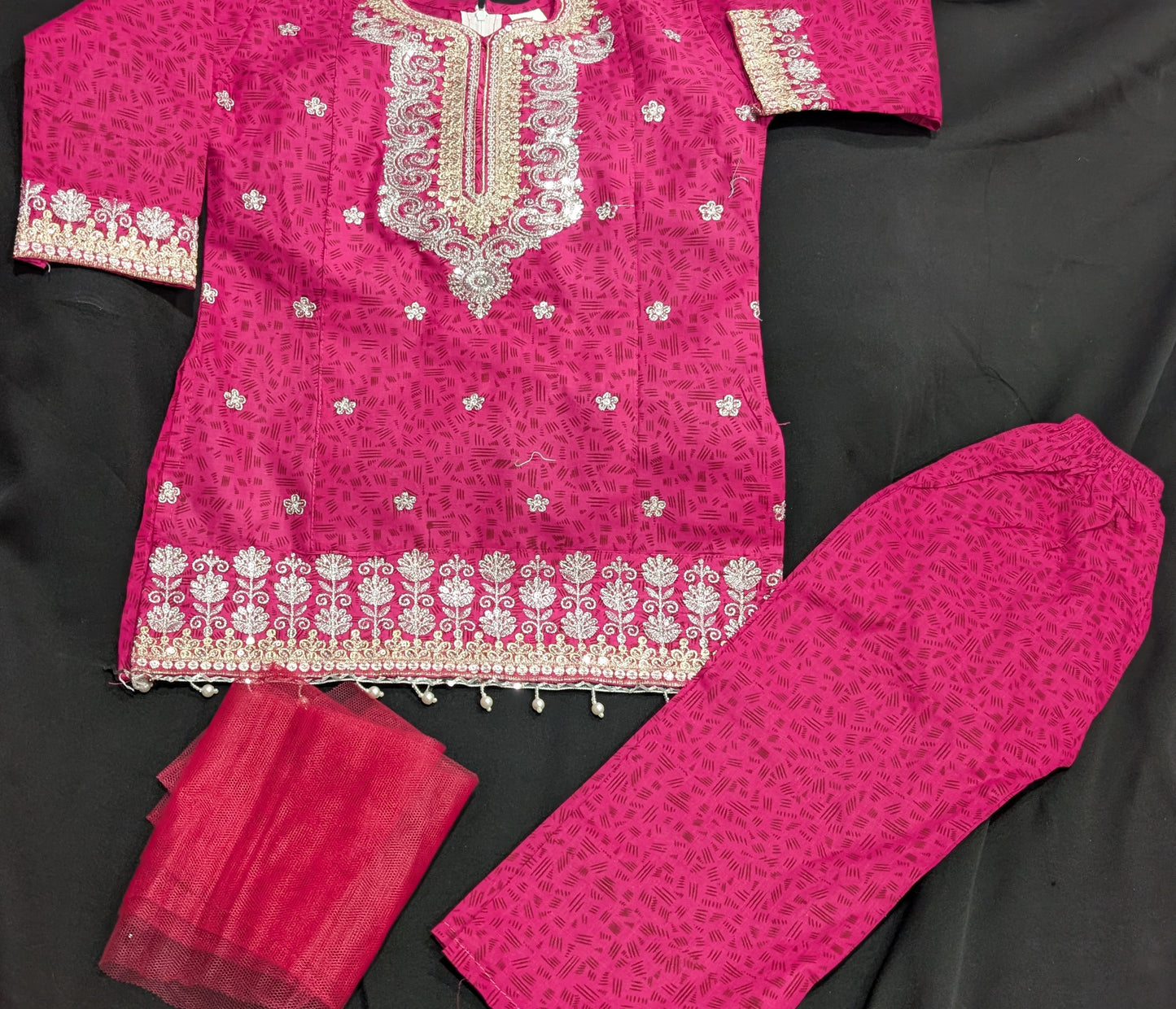 A girls' pink cotton kurta featuring a self-print and embroidery, paired with matching pants and a net dupatta.