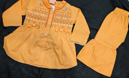 Infant  peach-orange peplum outfit  a high neckline, crystal buttons,  geometric embroidery, and matching flounced garara pants.