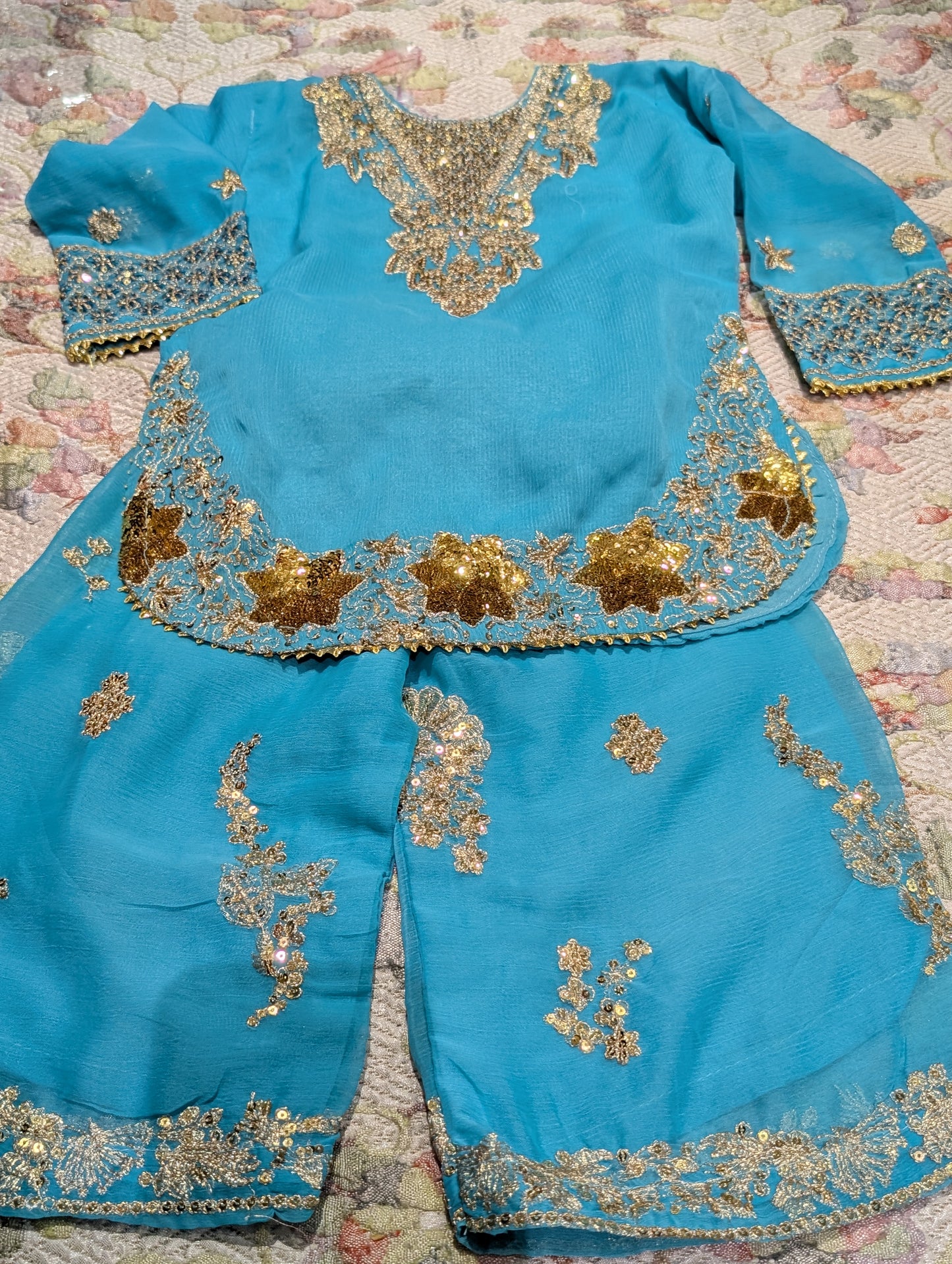 Girls turquoise gharara pants  featuring intricate, heavy gold embroidery, sequins, and zardozi-style detailing along the neckline, cuffs, curved hem, and pants.