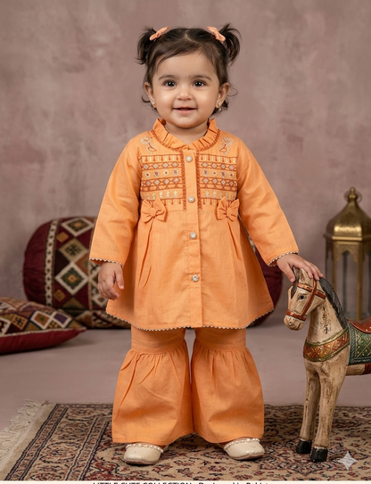 Infant  peach-orange peplum outfit  a high neckline, crystal buttons,  geometric embroidery, and matching flounced garara pants.