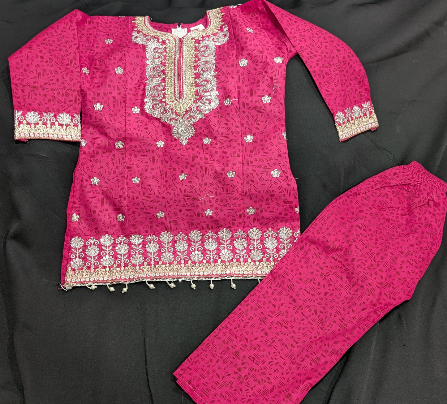 A girls' pink cotton kurta featuring a self-print and embroidery, paired with matching pants and a net dupatta.