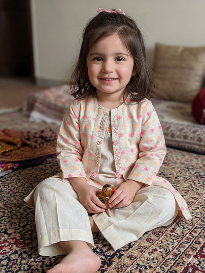 Girls light cream jacket with pink, orange, and gold geometric embroidery and beaded trim, layered over a solid off-white tunic and matching pleated wide-leg trousers,